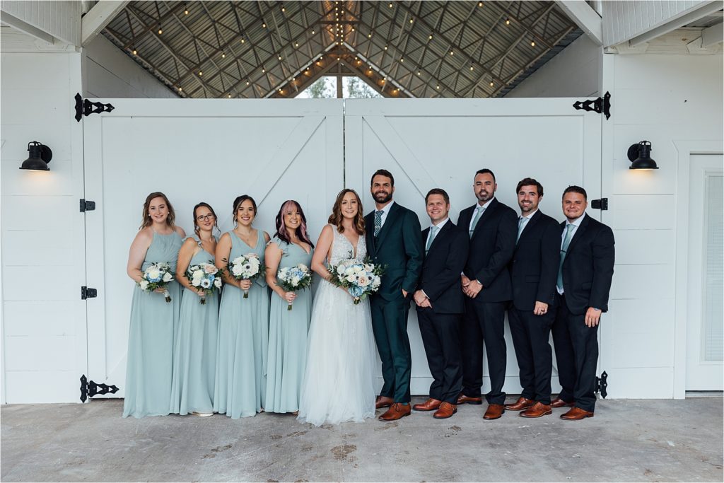 full bridal party standing together smiling at camera