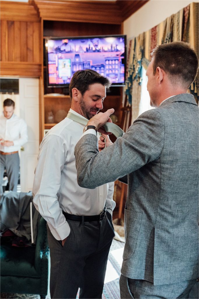 close up of groom getting tie put on